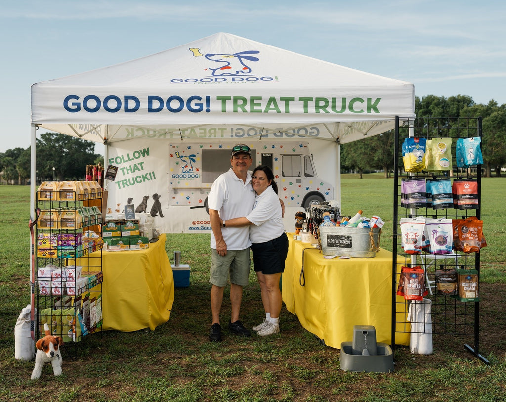 Anne and her husband standing in front of their product tent at an event